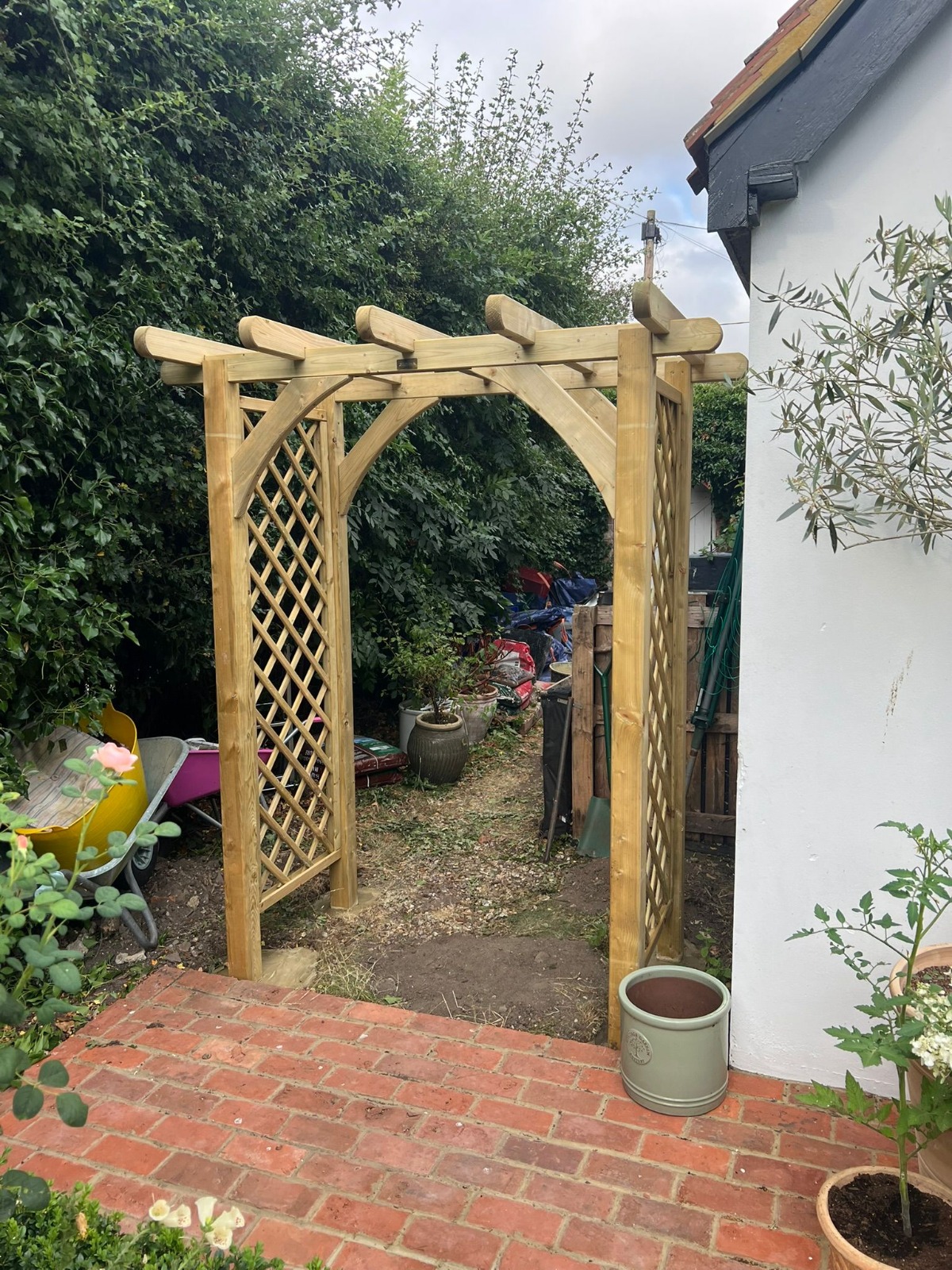 Timber archway on a brick-paved patio